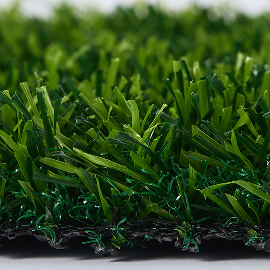 Close-up side view of green artificial grass fibers and backing