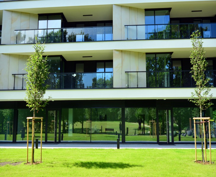An office or commercial building frontage bordered by trees and a green lawn